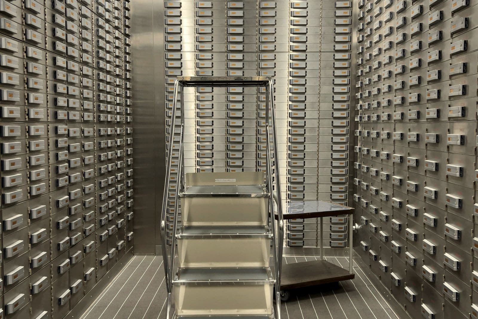 Rows of numbered safe deposit boxes lining a bank vault room
