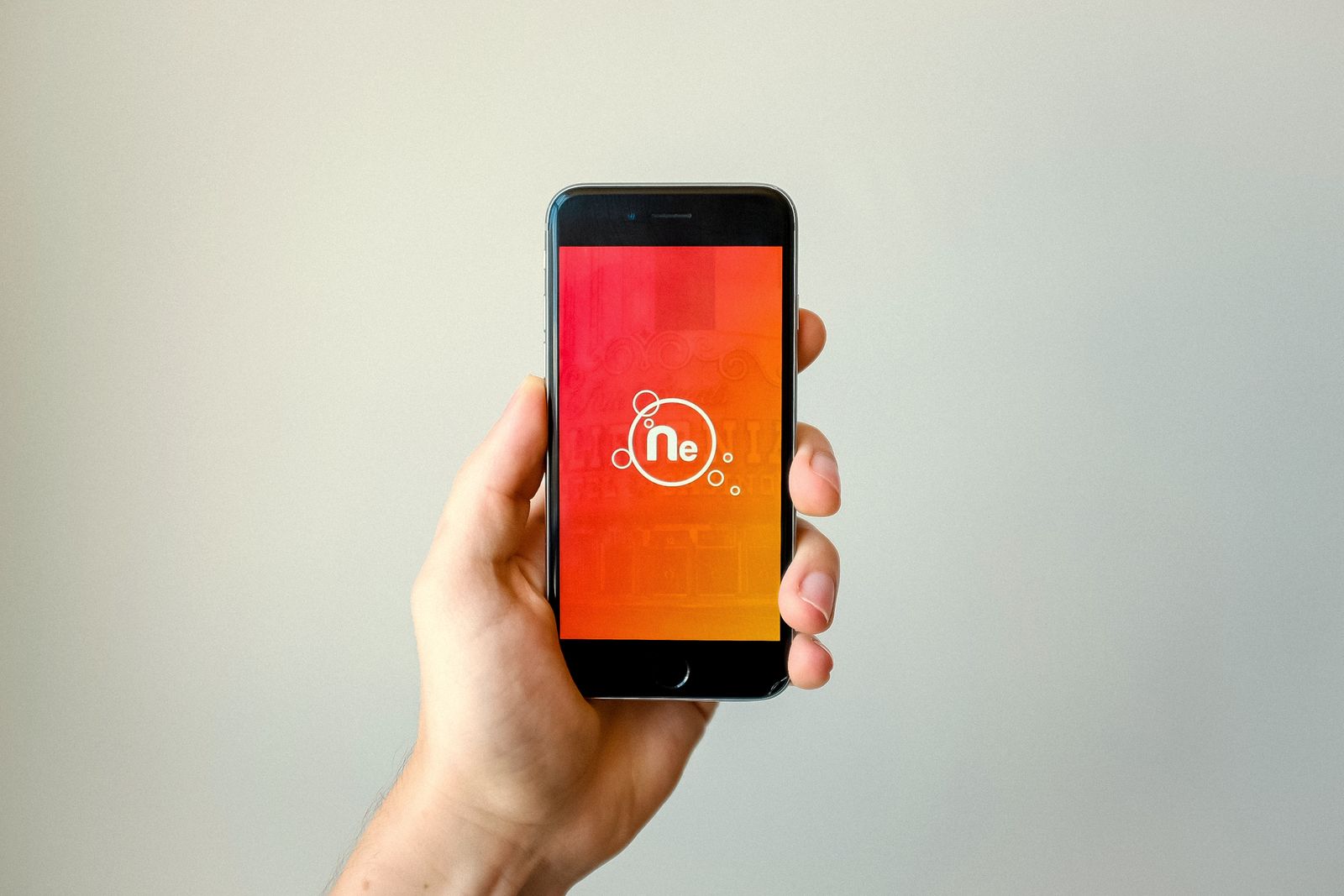 A hand holding a smartphone showing an app's start screen