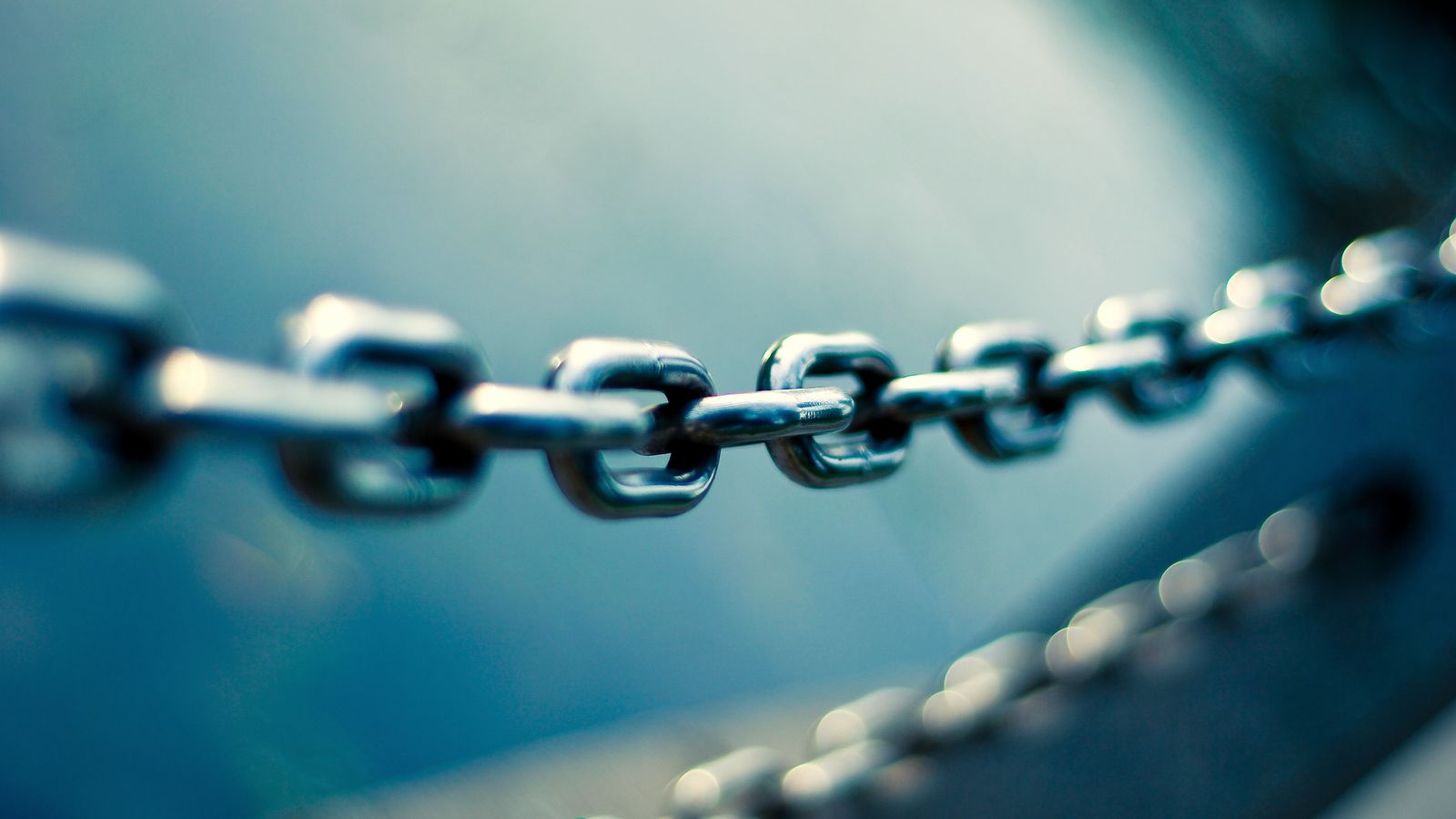 Close-up of a steel chain against a blue background