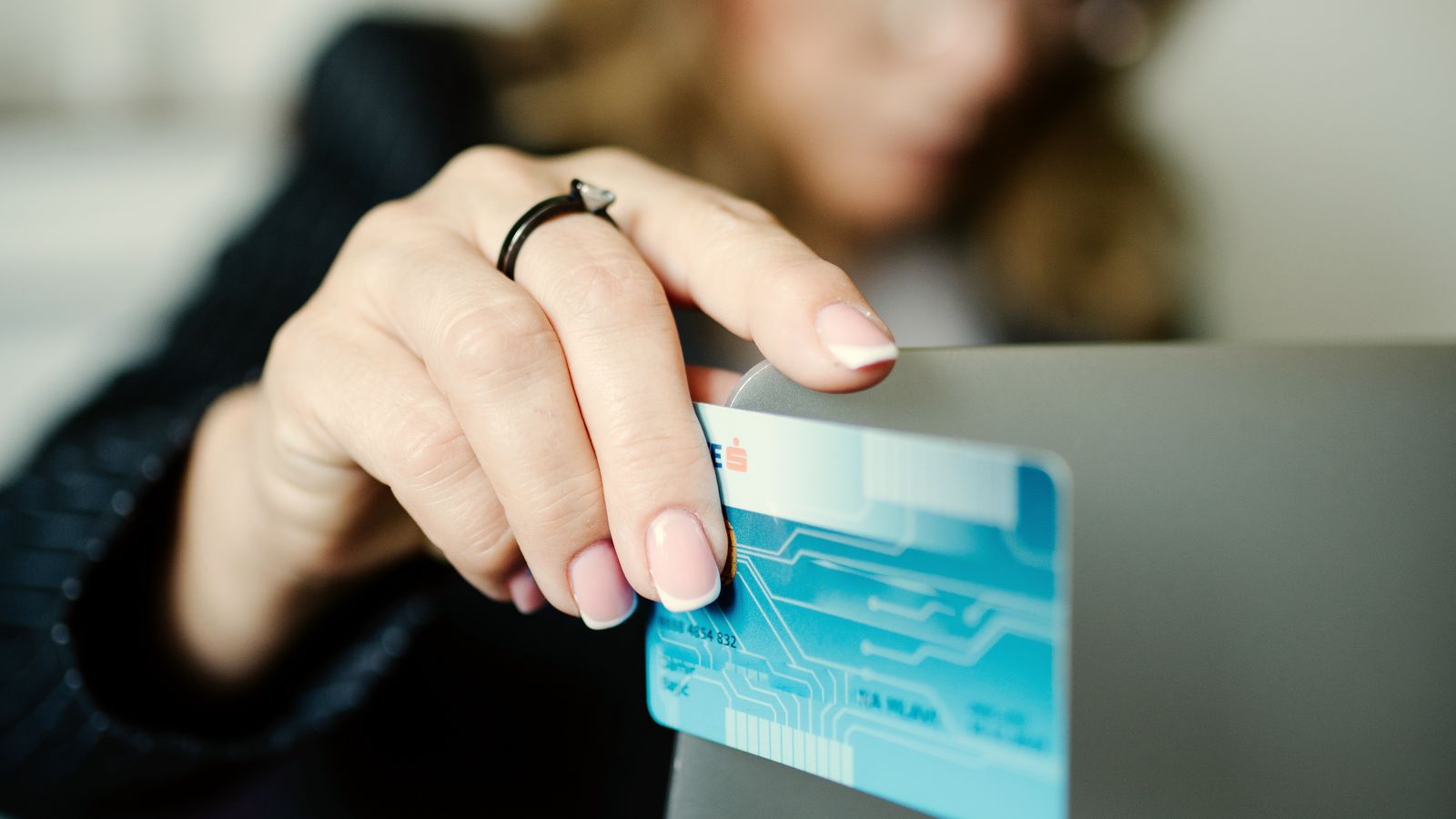 A person holding a payment card while shopping online on a laptop
