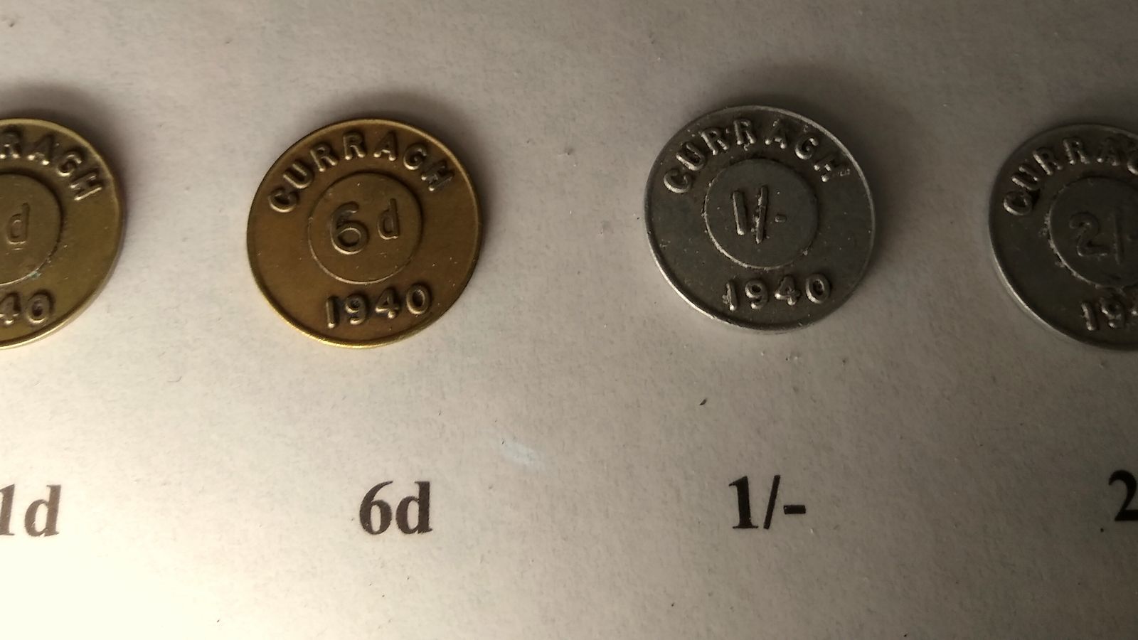 Four old metal tokens of different values laid out in a row