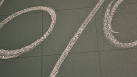 A large percent sign drawn in chalk on a grey board