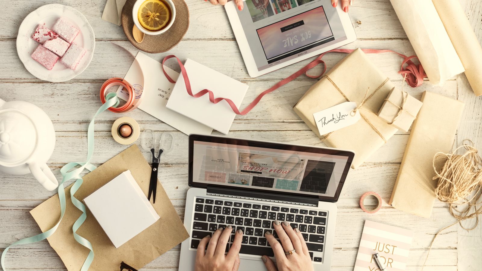Hands typing on a laptop surrounded by parcels and gift wrapping