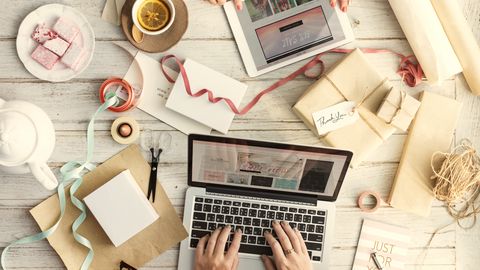 Hands typing on a laptop surrounded by parcels and gift wrapping