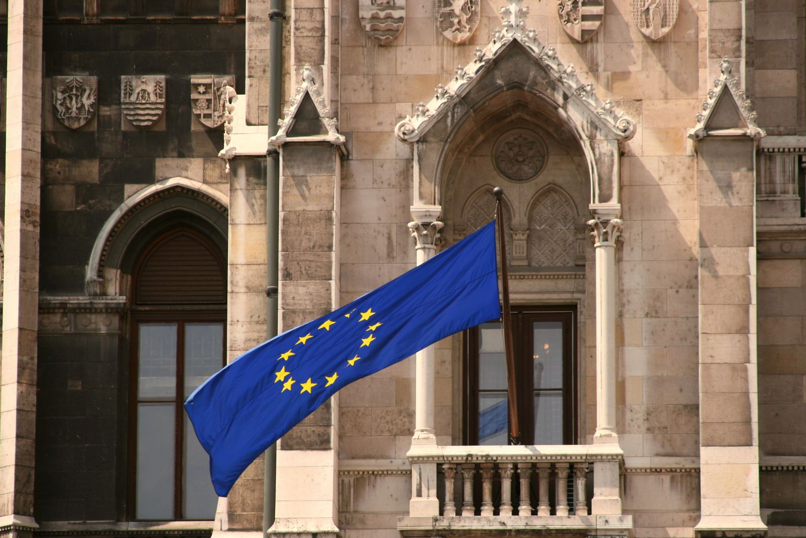 An EU flag hanging from the balcony of a historic stone building