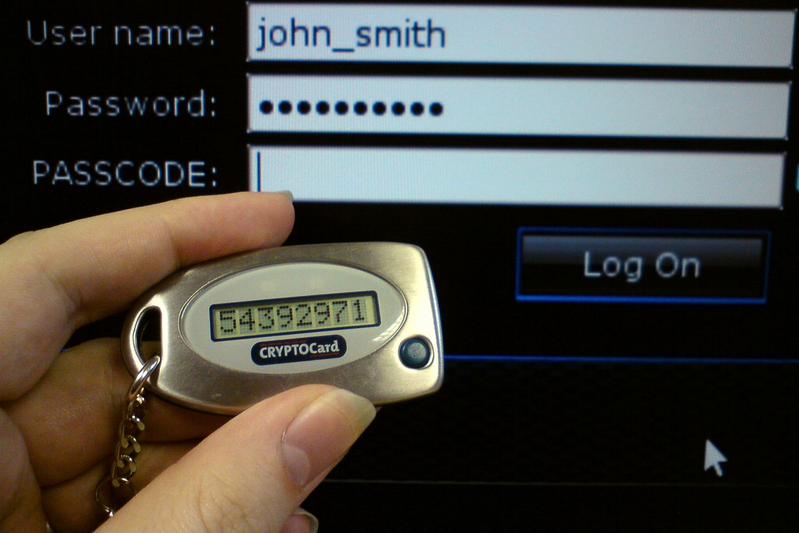 A key-fob security token showing a one-time passcode beside a login screen