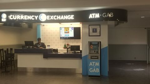 A currency exchange counter with a cash machine in an airport