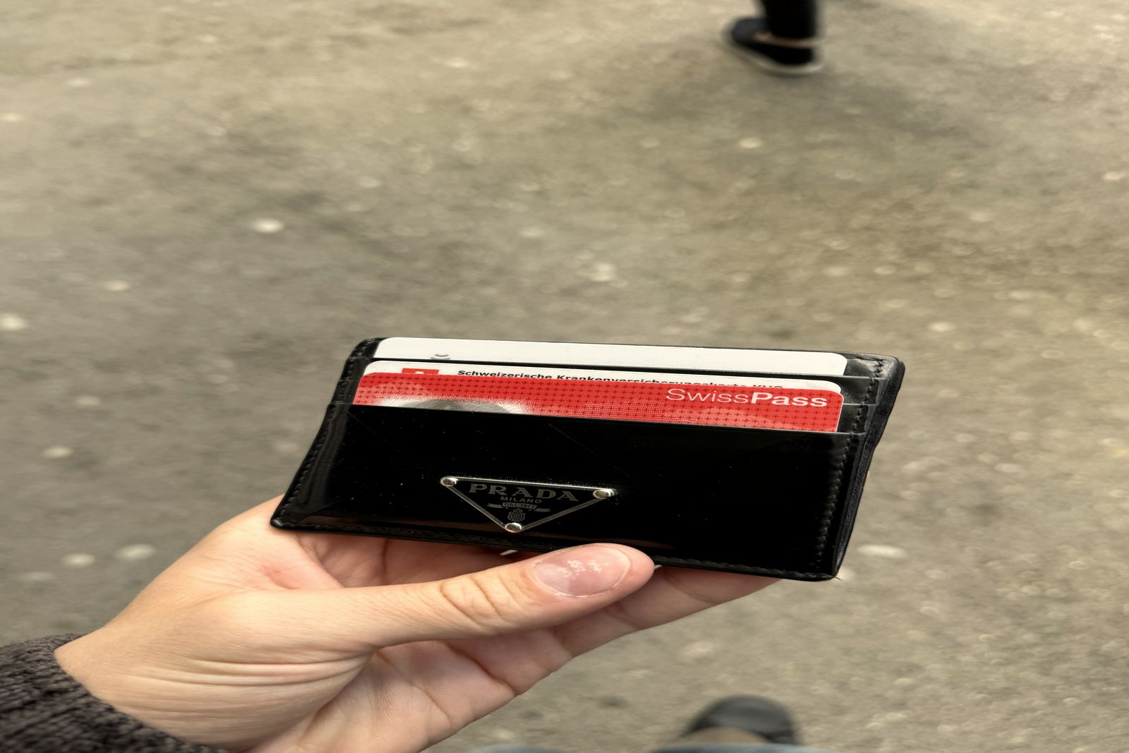 A hand holding a slim card wallet with several payment cards