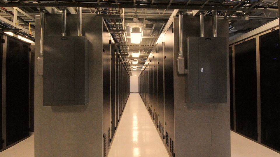 A narrow aisle between black server cabinets in a data centre