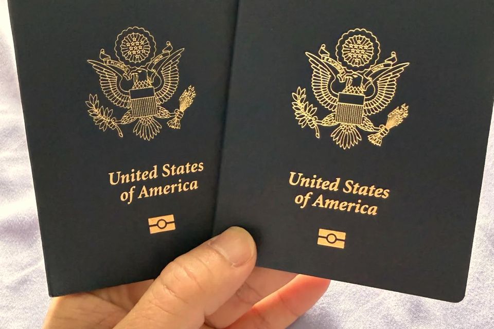Two US passport booklets held in a hand