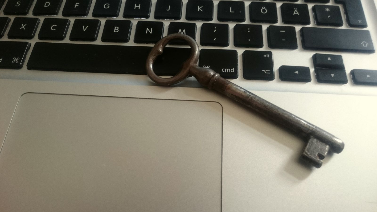An old iron key lying on a laptop keyboard