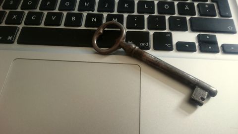 An old iron key lying on a laptop keyboard