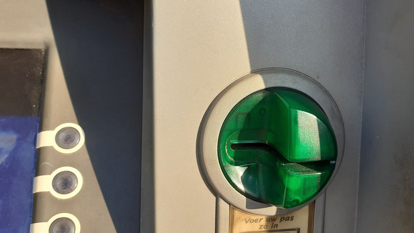 A green anti-skimming guard fitted around a cash machine's card slot