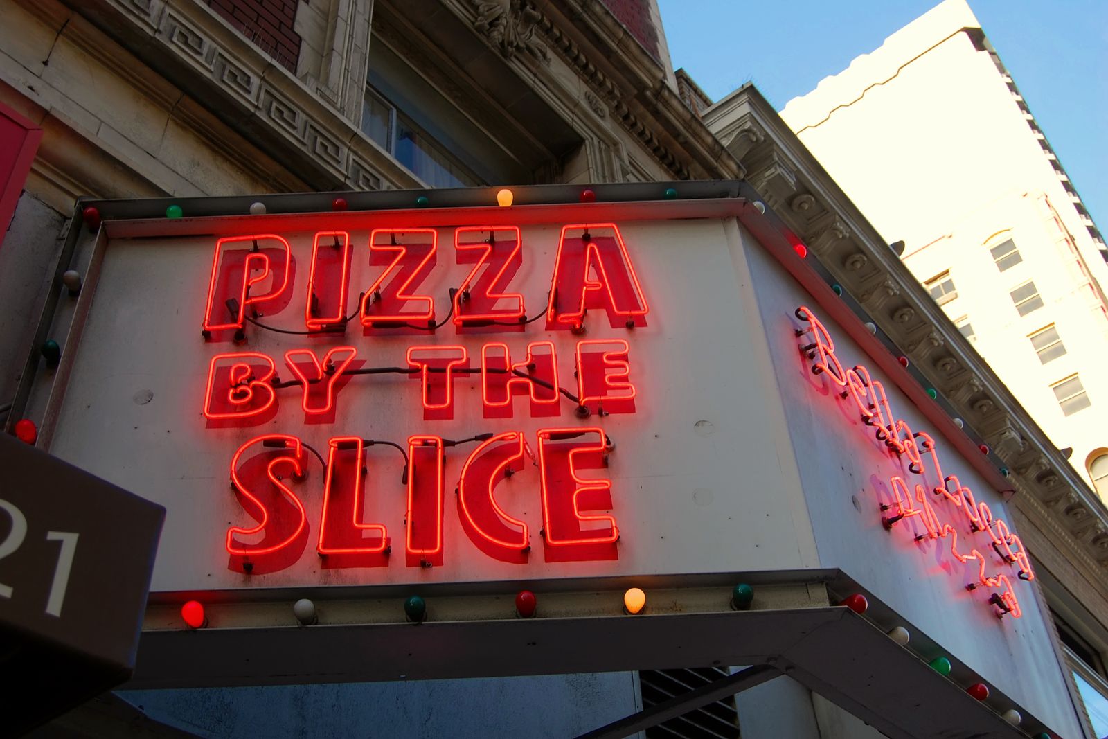 A restaurant sign advertising pizza by the slice